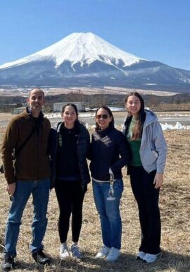 Four tourists enjoy the scenic view of Mount Fuji from a popular viewpoint, capturing memories on a sunny day.