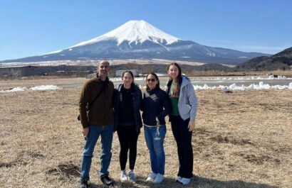 Four tourists enjoy the scenic view of Mount Fuji from a popular viewpoint, capturing memories on a sunny day.