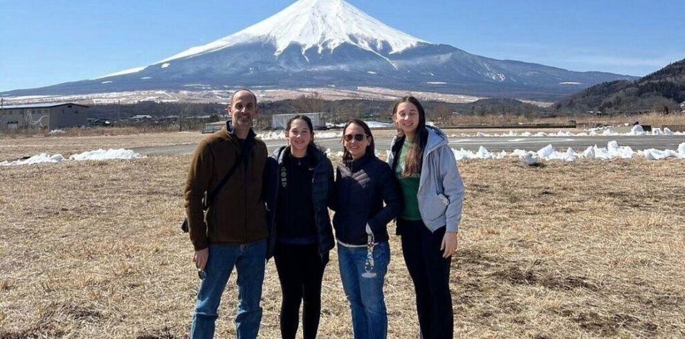Four tourists enjoy the scenic view of Mount Fuji from a popular viewpoint, capturing memories on a sunny day.